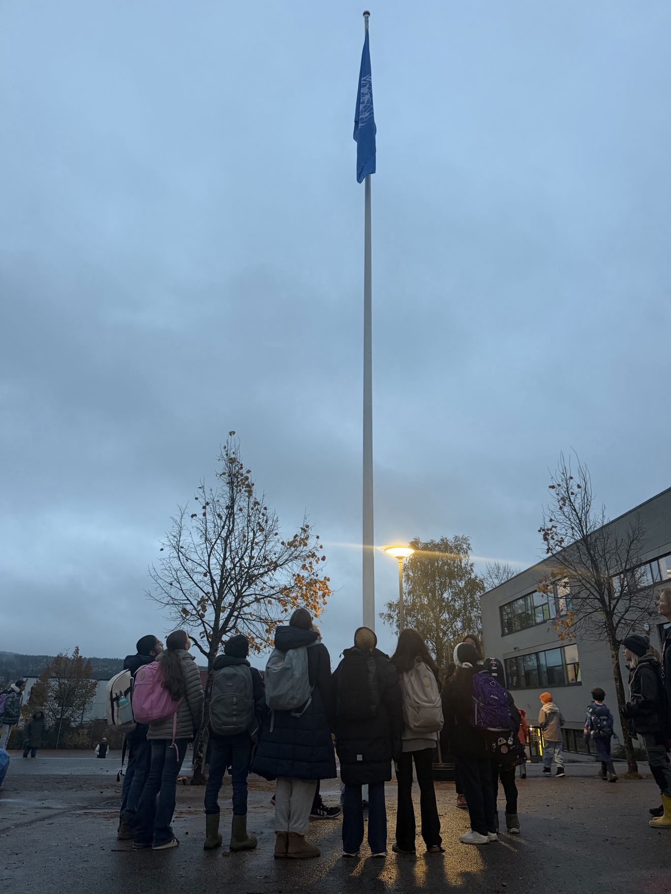 En gruppe mennesker som står foran en flaggstang