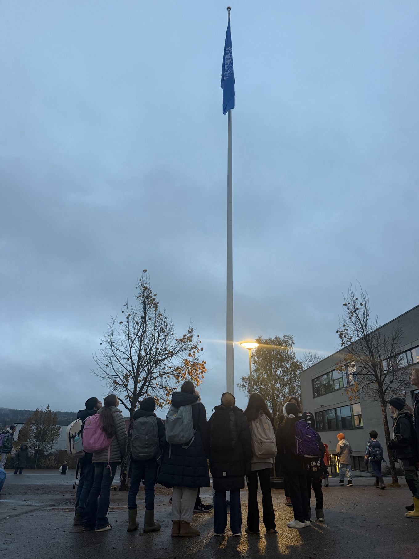 En gruppe mennesker som står foran en flaggstang