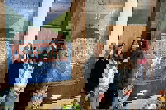 en gruppe mennesker som poserer for et bilde foran et maleri