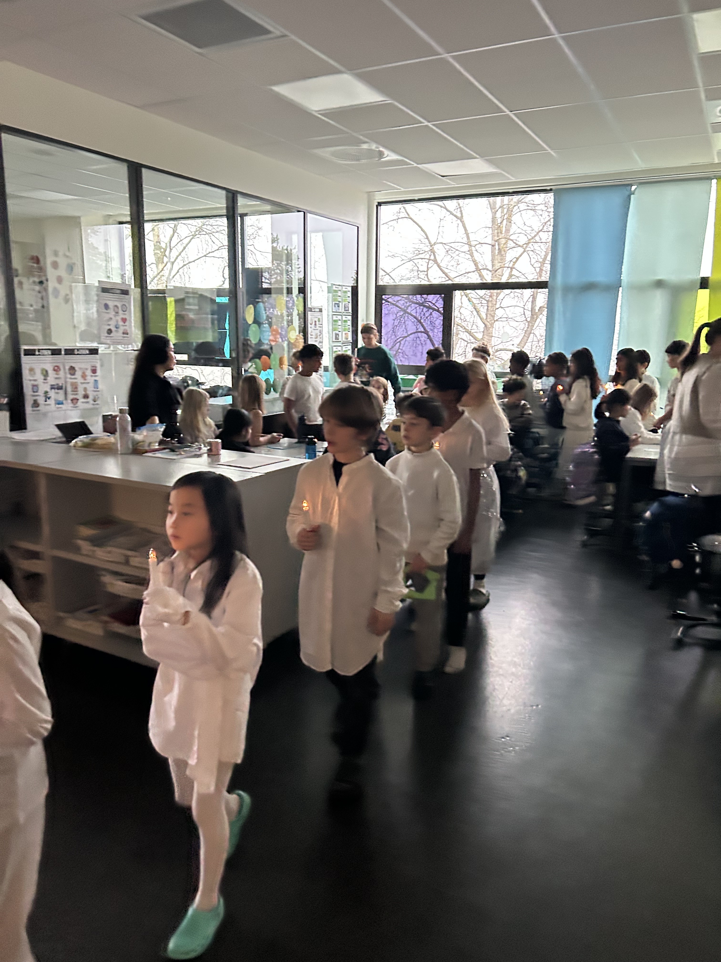 En gruppe barn i hvite karateuniformer i et rom med folk