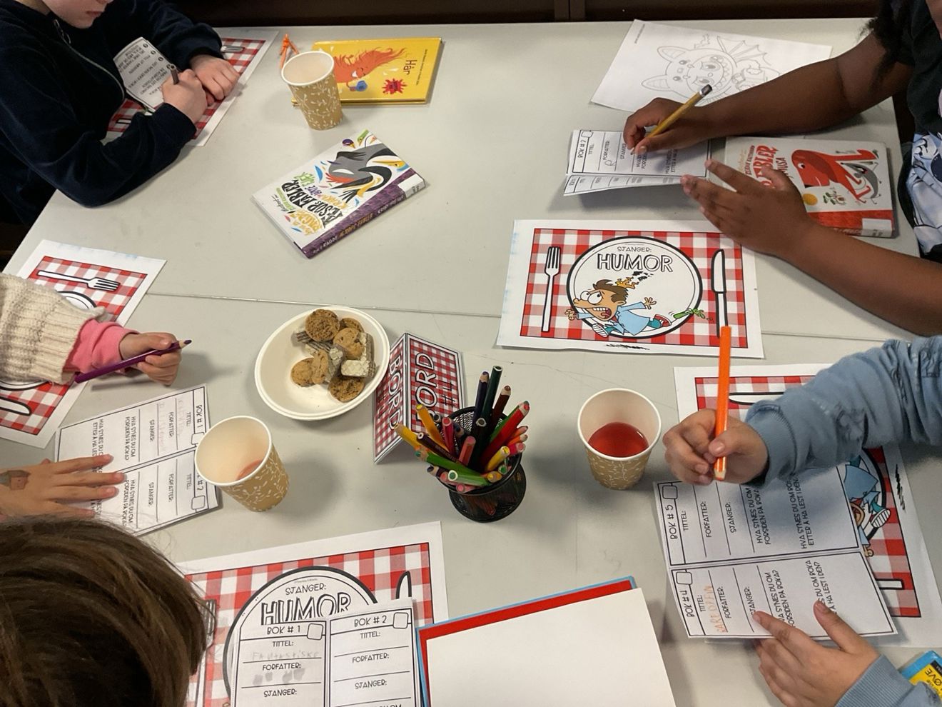 En gruppe mennesker som sitter rundt et bord med mat og drikke En gruppe mennesker som sitter rundt et bord med mat og drikke